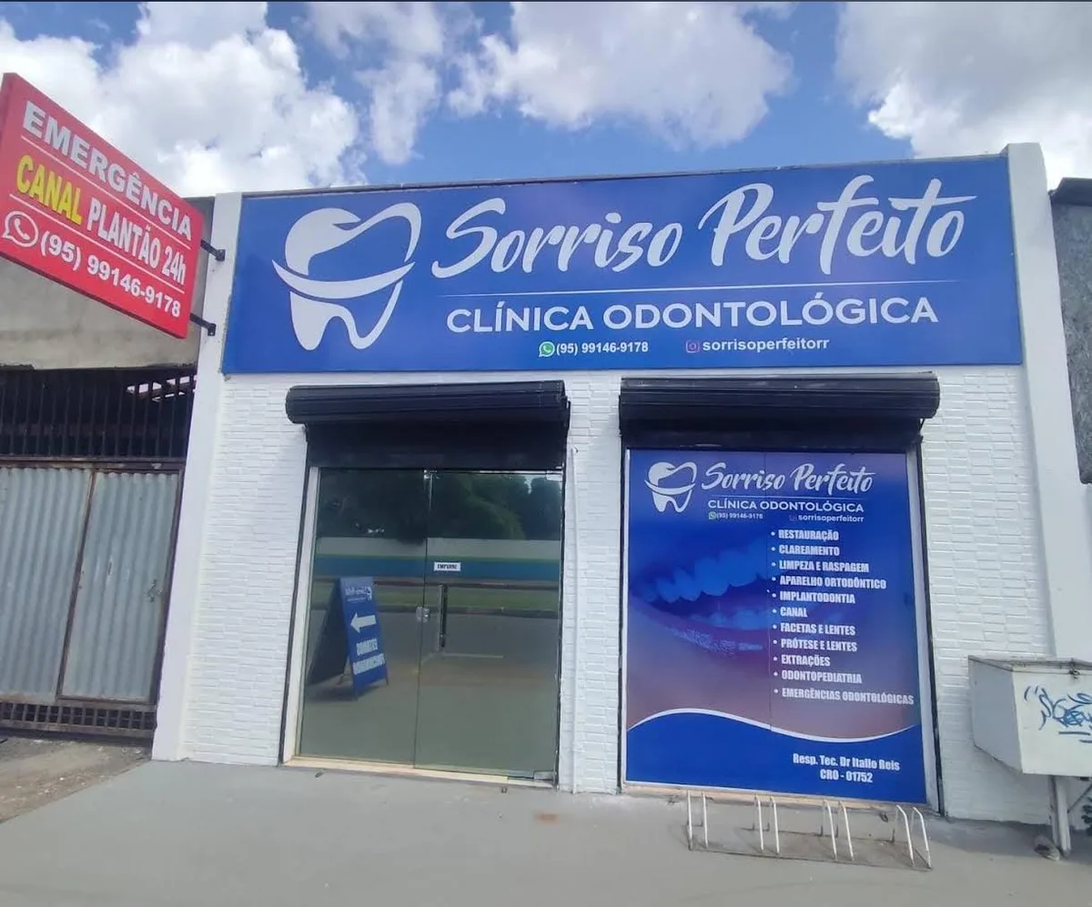 Fachada da clínica Sorriso Perfeito em Boa Vista/RR, com a placa azul da marca e a porta de vidro da entrada